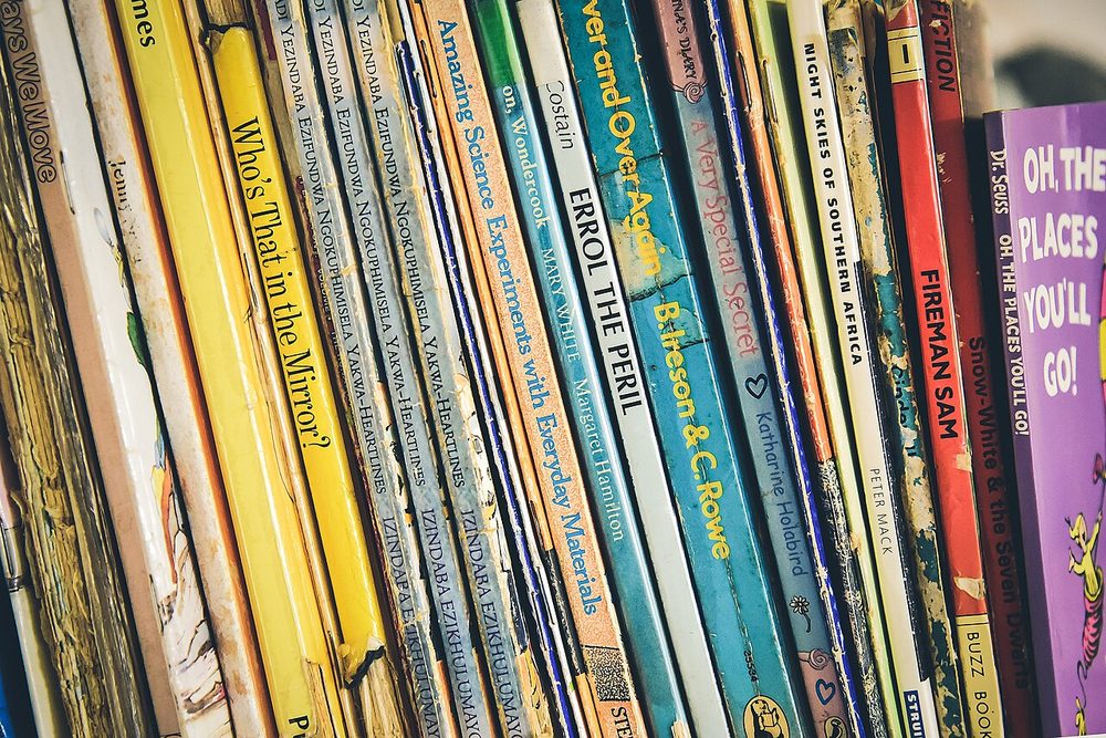 The spines of children's books standing on a shelf